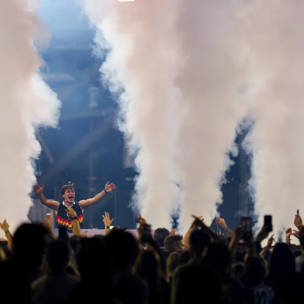 Ekstase beim Sunset-Event: DJ BUNT. feiert hinter dem Pult inmitten von riesigen Nebelsäulen vor einer begeisterten Menge im Hangar-7.