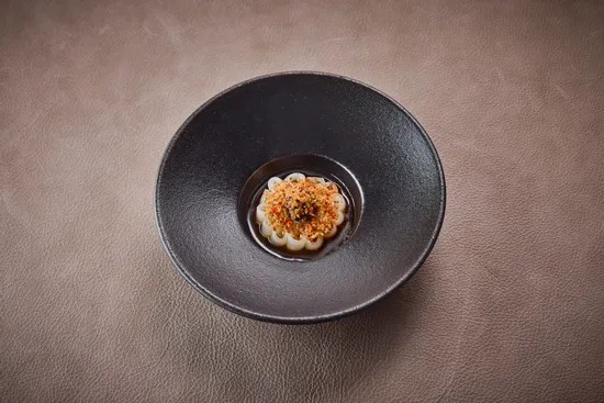 Teller mit Gericht, Tintenfisch – schwarzer Knoblauch – gegrillte Zitrone