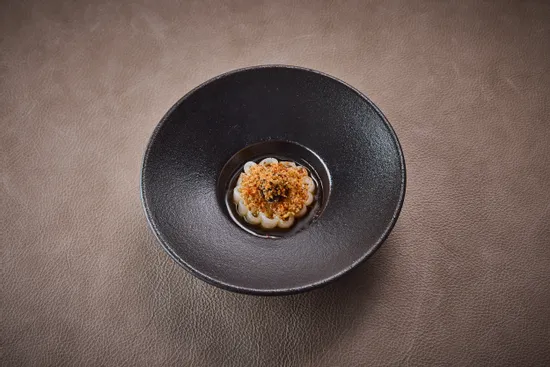 Teller mit Gericht, Tintenfisch – schwarzer Knoblauch – gegrillte Zitrone